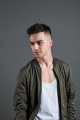 Obraz premium Young serious man posing in studio. Gray background