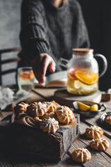 A woman reaches for a cake and drinks grapefruit tea. Healthy drink.