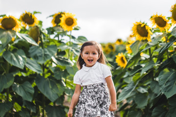 Pretty girl standing among sunflowers