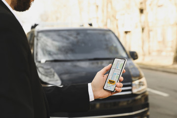 Businessman ordering taxi with smartphone on city street, closeup