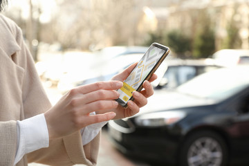 Woman ordering taxi with smartphone on city street, closeup