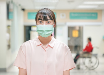 Fototapeta na wymiar Asian female wearing medical mask with blur out patient department in hospital