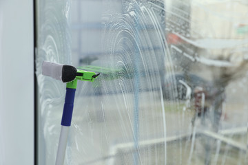 Cleaning window with squeegee indoors. Space for text