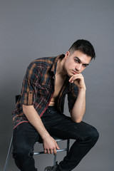 Young serious man posing in studio. Gray background