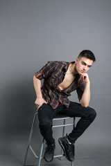 Young serious man posing in studio. Gray background