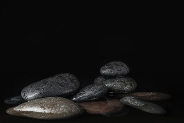 Stones in water on black background, space for text. Zen lifestyle