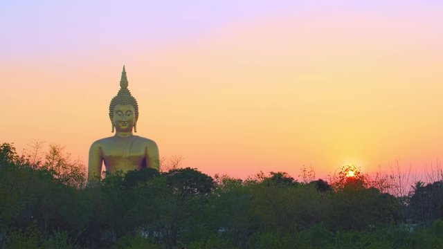 sunset behind the bigest Buddha statue at Wat Muang Ang Thong Thailand.