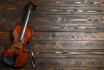 Fototapeta na wymiar Classic violin and bow on wooden background, top view. Space for text