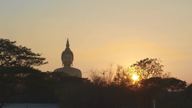 sunset behind the bigest Buddha statue at Wat Muang Ang Thong Thailand.