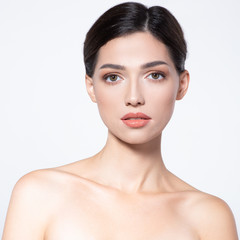 Obraz premium Beautiful face of young woman with health fresh skin. Portrait of beautiful brunette woman with clean face. Beautiful face of young adult woman with clean fresh skin - isolated on white. Skin care.