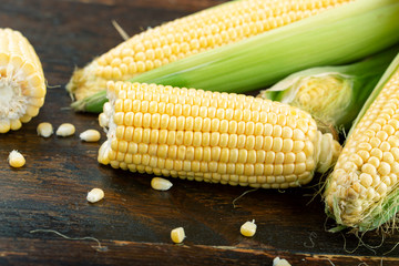Fresh corn on cobs on wooden table.