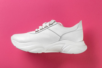 Fashion shoes on colorful background. New white sneakers on pink  background, copy space.