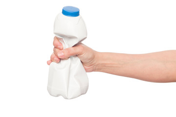 Woman's hand holding a crushed white milk bottle isolated on white background