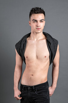 Sexy young man posing in studio. Gray background