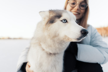 Happy young girl playing with siberian husky dog in winter park