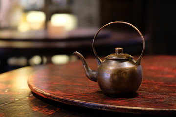 close up one old copper teapot on wooden table. Traditional Chinese tea kettle. Bokeh background