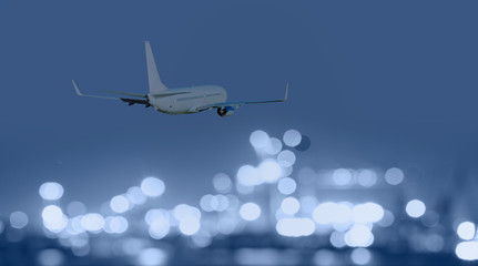 Airplane flies over the city of night with bokeh