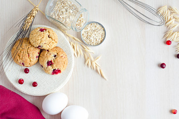 top view, flat lay, cooking oatmeal cookies with ingredients, cranberries and cereals, on light wooden background, copy space