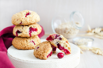 oatmeal cookies in break with cranberries and cereals, on light wooden background, soft focus