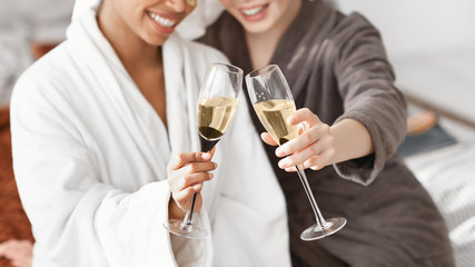 Cropped of two multiethnic spa girlfriends holding glasses of champagne