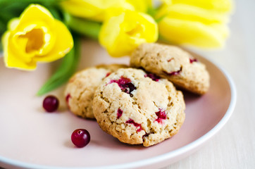 oatmeal cookies with cranberries and cereals, with yellow tulips. morning bouquet and breakfast, soft focus
