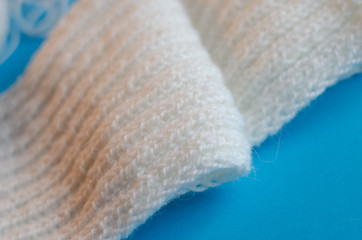 Fototapeta na wymiar Knitting a scarf from wool yarn. Scarf made of white threads on a blue background.
