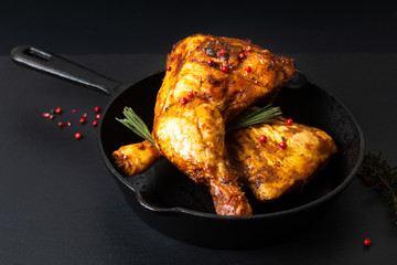 Food concept organic roasted or grilled chicken leg quarters in skillet iron pan on black slate...