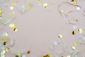 Pink confetti and feathers and sparkles on pink background. Top view, flat lay. Copyspace for text. Bright and festive holiday background. For Easter, New year, Mother's day.