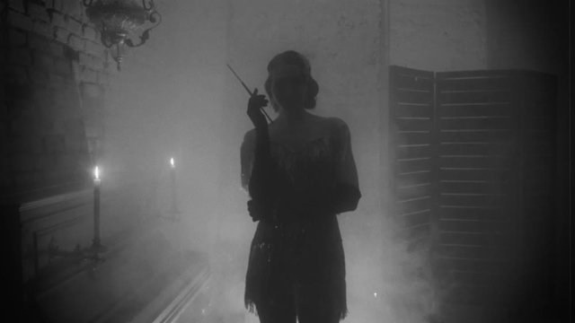 Imitation black and white old fashioned movie grain added for 20s style. Portrait Beautiful silhouette sexy woman. mouthpiece in hand. vintage dress. Background room burning candle sparkle smoke piano