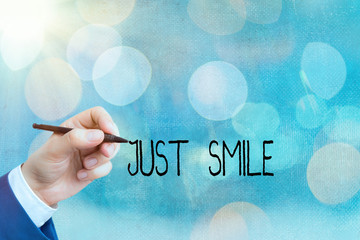 Conceptual hand writing showing Just Smile. Concept meaning assume a facial expression indicating...