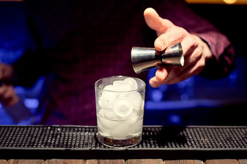 Fototapeta na wymiar Night club bartender man making a cocktail in a glass with ice.