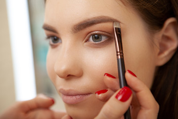 Unrecognizable professional makeup artist doing eyebrows of a female client, working at beauty...