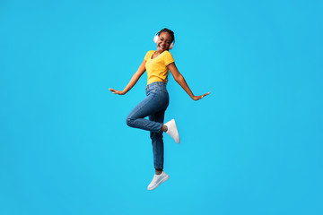 Fototapeta na wymiar Girl In Earphones Jumping And Singing Song On Blue Background