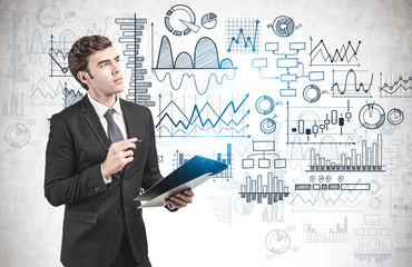 Thoughtful man with clipboard, graphs on wall
