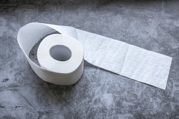 Roll of white soft toilet paper on dark background. Personal hygiene concept. Flat lay, top view.
