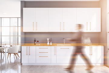 Man walking in spacious gray kitchen with table