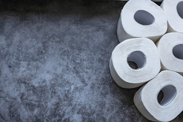 Rolls of white soft toilet paper on dark background. Personal hygiene concept. Flat lay, top view. Copy space.