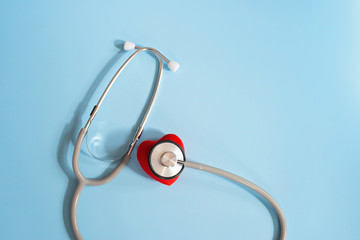 Stethoscope and red heart on a blue background. Cardiology and heart health concept. The medicine....