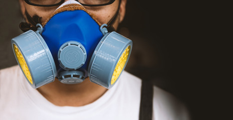 closeup men wearing respirator mask industrial cartridge filter anti-dust safety chemical with soft-focus and over light in the background - obrazy, fototapety, plakaty