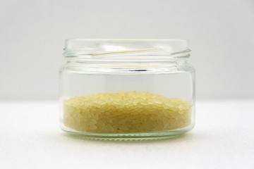 Glass jar with rice on a white background, side view.