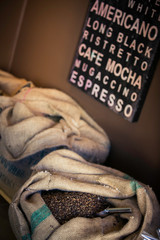 Coffee Beans in Burlap Sack with Coffe Words on Painting in Background