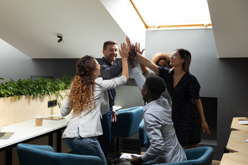 Happy diverse employees team giving high five at briefing, celebrating business achievement,...