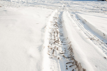 Tire tracks on a road covered by snow. Cold winter day.