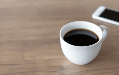hot coffee cup on wooden table with soft-focus and over light in the background