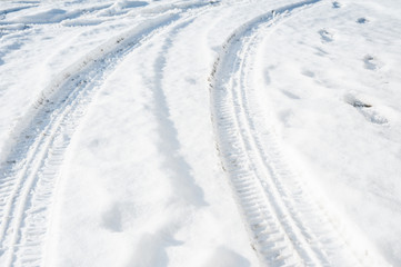 Tire tracks on a road covered by snow. Cold winter day.
