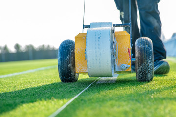 Fototapeta premium drawn white lines on the football field with white paint on the grass using a special machine before a game