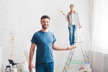Man holding wife on palm while she painting walls