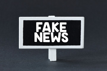 FAKE NEWS. The word FAKE NEWS inscribed on a small chalk board and a black background.