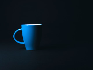Blue mug on an isolated black background. Mug of on a background in the studio. 