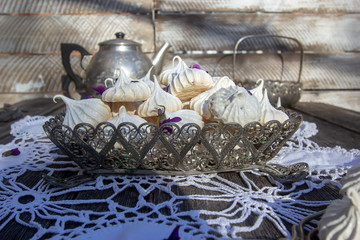 homemade meringues decorated with fresh violet flowers in a vintage metal candy cane